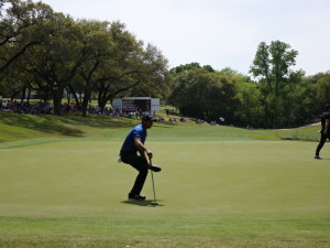 Jason Day stretches on the 9th green while waiting for Brooks Koepka to putt for birdie